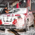 A technician cleaning a car with foam at Biswas Automobiles, showcasing high-quality car wash services in Dhaka.