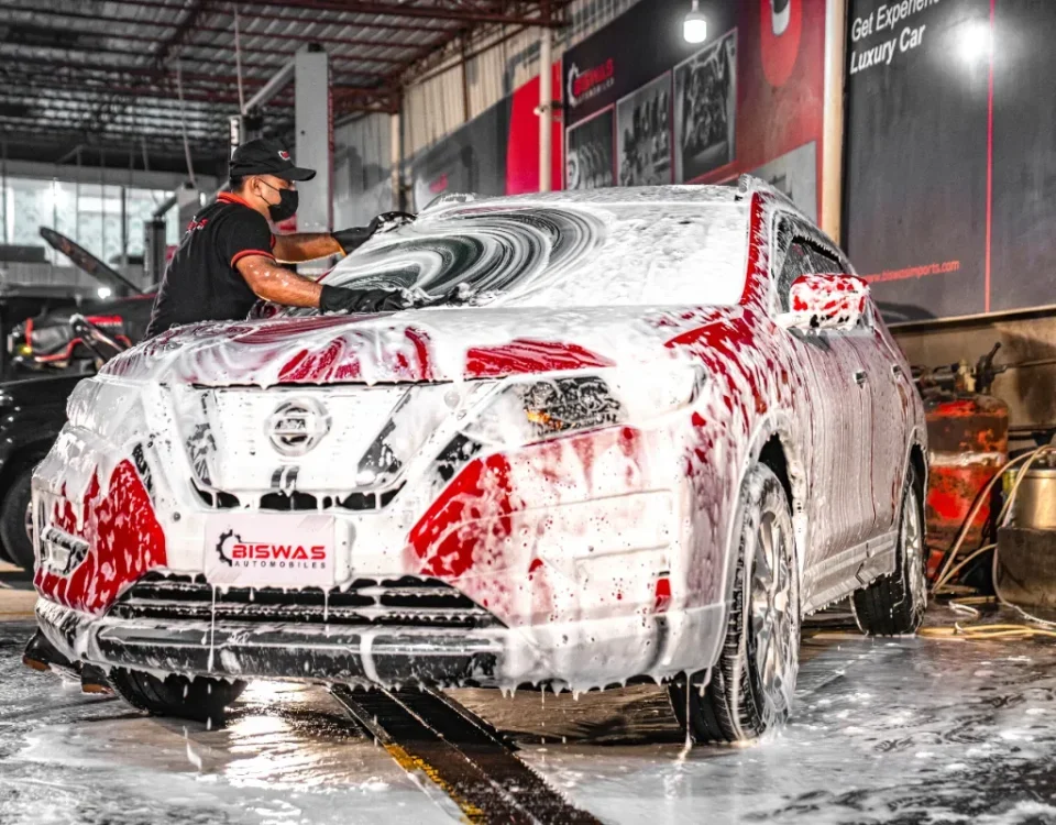 A technician cleaning a car with foam at Biswas Automobiles, showcasing high-quality car wash services in Dhaka.